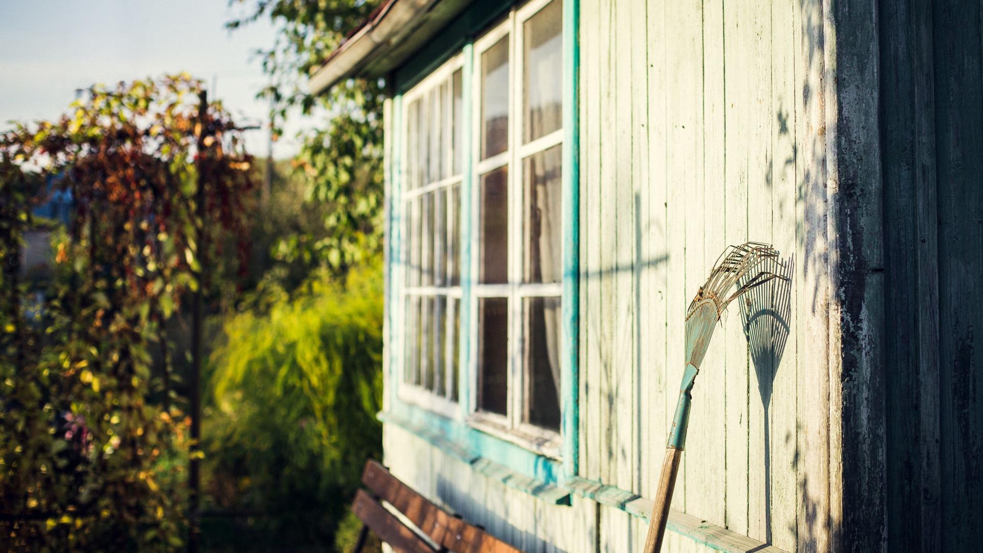 rake leaning up against a garden shed