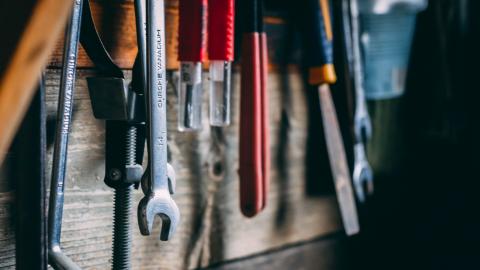 An assortment of tools hanging on a wooden wall