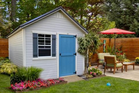 White garden shed with bright blue door in a stylish backyard